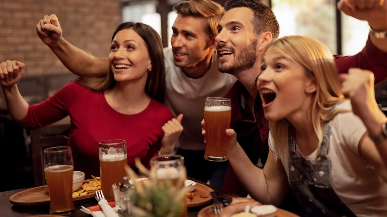 Amigos comemorando enquanto assistem a um jogo de futebol em um bar